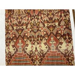 Ikat Man’s Cloth (Hinggi Kombu), East Sumba, Indonesia, woven in red, blue and yellow-brown warp ikat, constructed of two mirroring long panels, the motifs arranged in four bands depicting warrior figures astride rearing horses, high-ranking figures and guardians within geometric borders, on carved wooden wall hanger, L295cm
