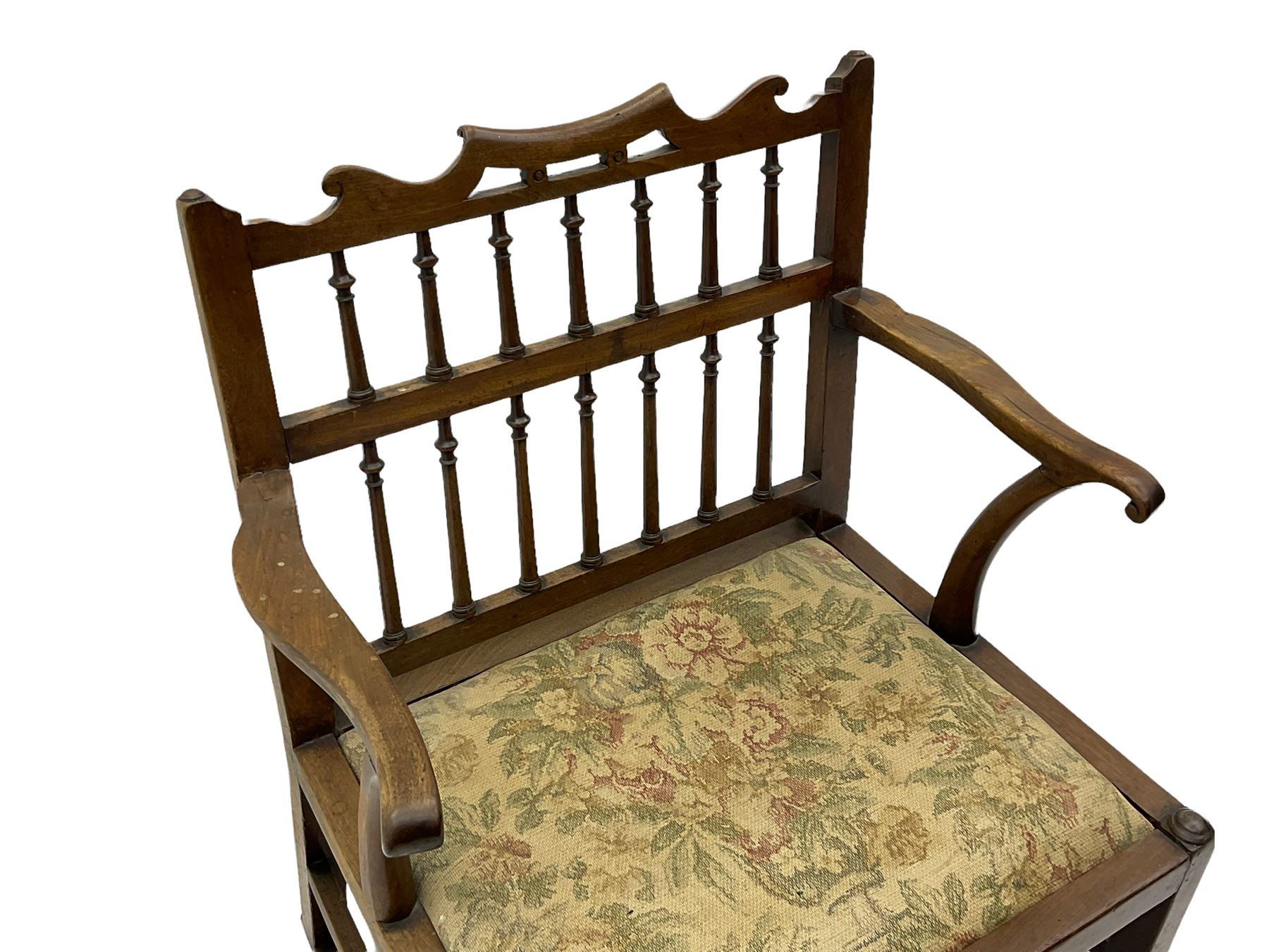 Late 18th century walnut 'Drunkard's' chair, the shaped cresting rail over spindle back, wide set seat with upholstered drop in cushion, shaped arms with scroll carved terminals, sledge supports with bracket feet joined by plain stretchers 
