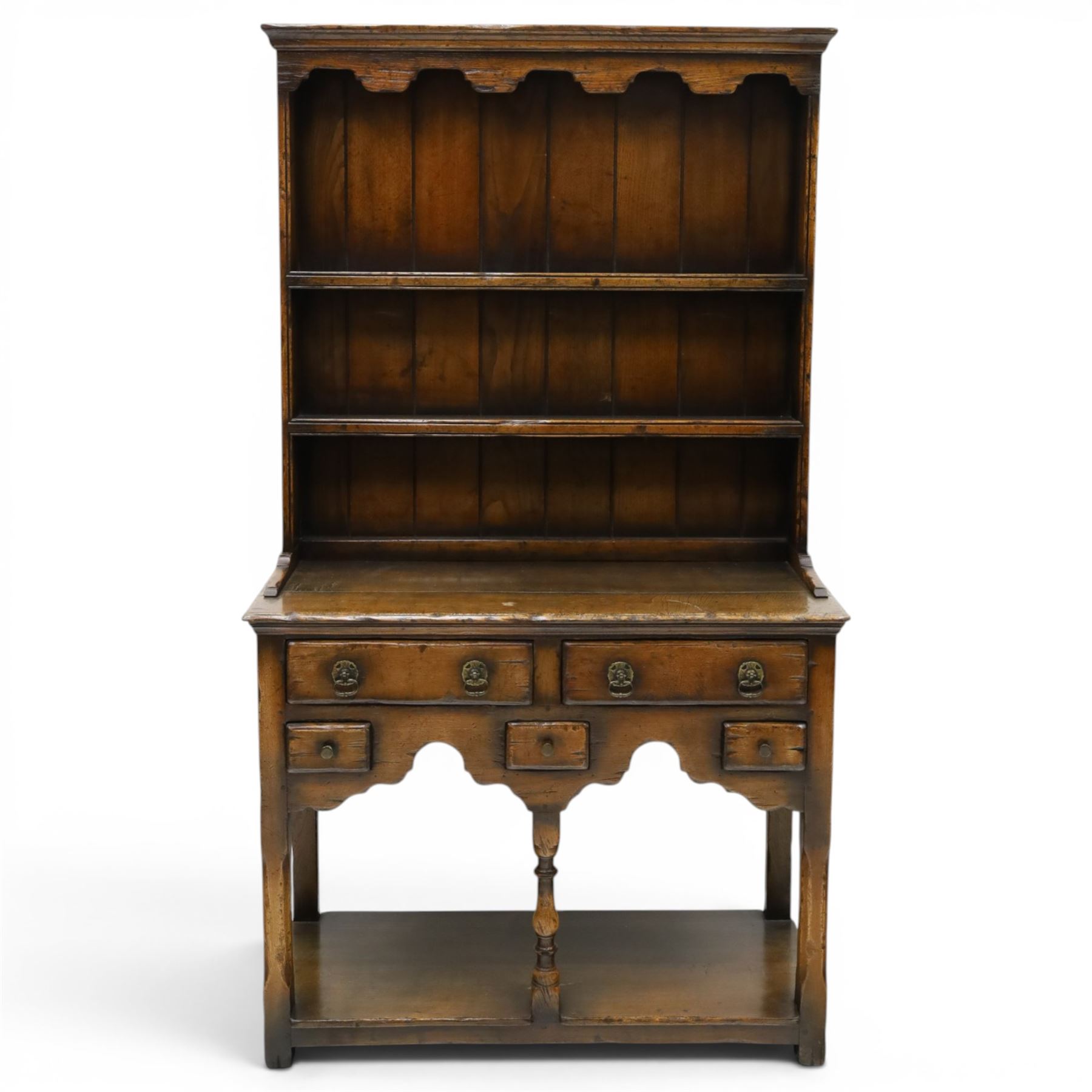 Georgian design oak dresser of small proportions, moulded cornice over open plate rack with two shelves and shaped apron, the base fitted with two drawers over three small drawers, brass drop handles, shaped apron, on square supports united by pot board