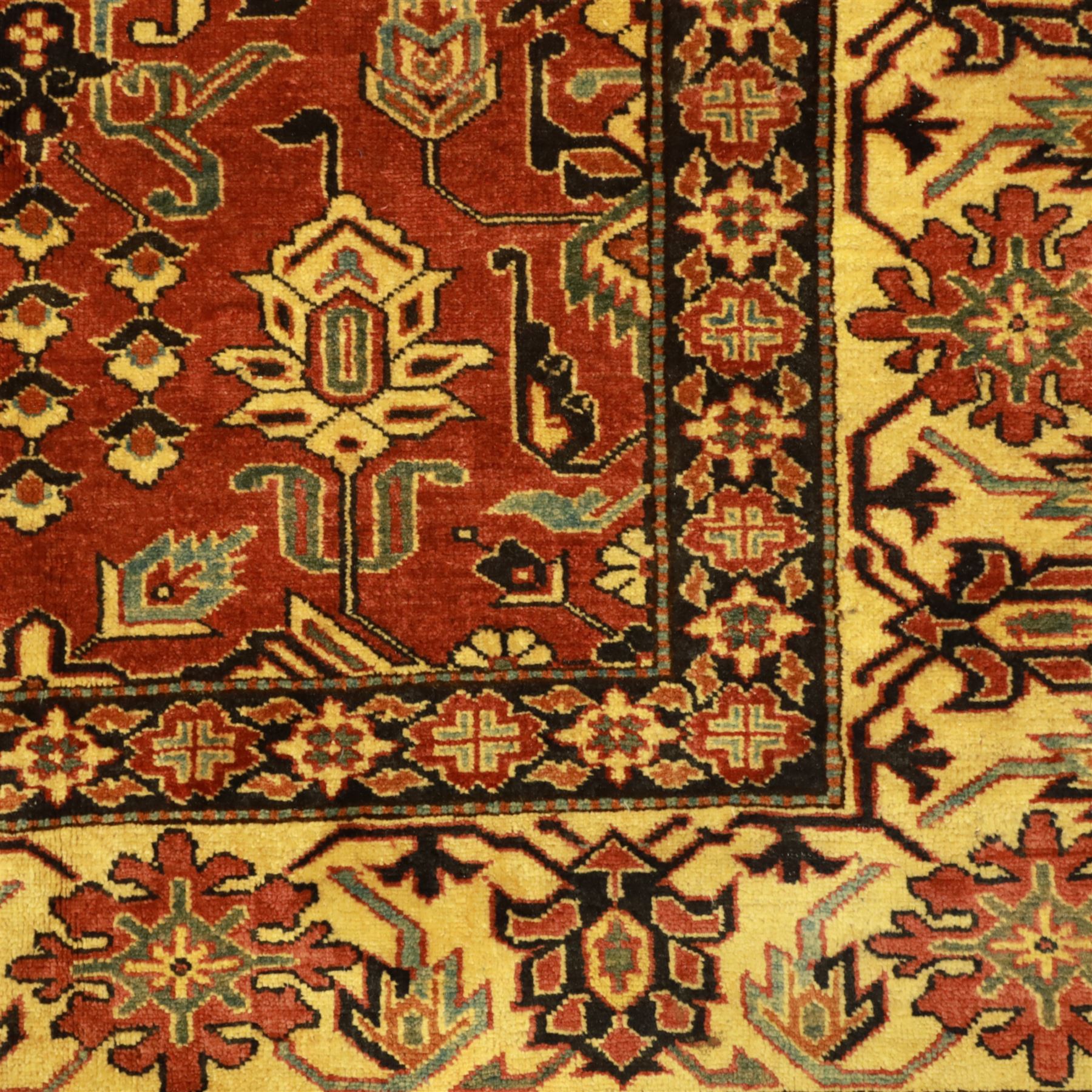 Afghan Gazni Kazak rug, the hand-knotted wool pile featuring a rust red ground with all-over geometric floral motifs in ivory and dark green, enclosed by a wide ivory border with stylised rosettes and angular vine decoration, fringed ends, from the region of Ghazni, Afghanistan