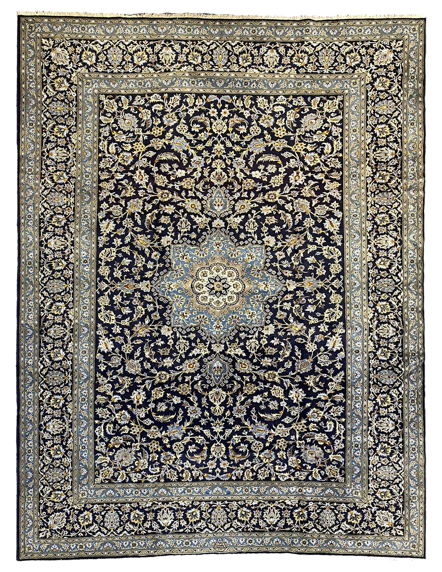 Central Persian Kashan indigo ground carpet, central lighter blue floral medallion surrounded by interlacing leafy branches and stylised plant motifs, the main border decorated with repeating floral motifs and scrolling branches, within guard stripes 