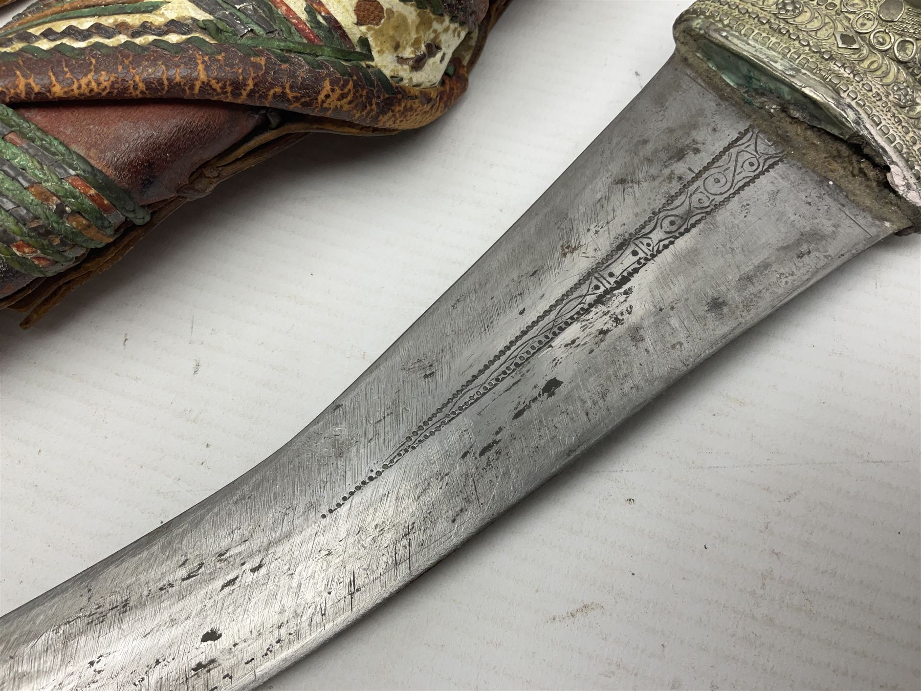 Saudi Arabian khanjar dagger with 29.5cm curving double edged  steel blade; white metal and copper mounted horn grip; in white metal mounted brass and leather scabbard incorporating embroidered leather wearing strap