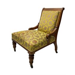 Late Victorian oak nursing chair, moulded frame with flower head carved roundels, upholstered in floral pattern fabric, on turned front feet with brass and ceramic castors 