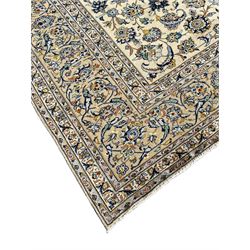 Persian Kashan carpet, the ivory ground field decorated with blue tone sweeping scrolled branch and stylised plant motifs, seven band border, the main band with scrolling design decorated with stylised floral motifs