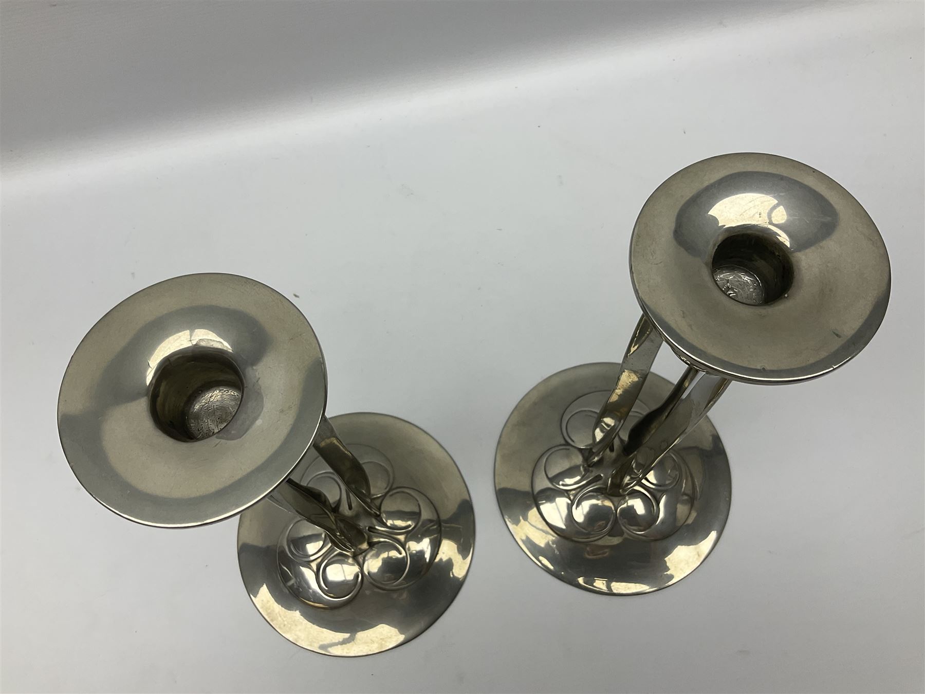 Archibald Knox (1864-1933) for Liberty & Co, pair of Tudric pewter candlesticks, the bud shaped sockets raised upon three angular fin supports and a slightly domed circular base with cast stylised foliate decoration, each stamped beneath Tudric 0223, H30cm