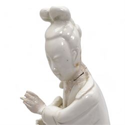 Chinese blanc de Chine figure of Guanyin, wearing robes and standing upon a lotus base, H25.5cm, a jichimu carved wooden stand, and carved greenstone figure of an immortal (3)
