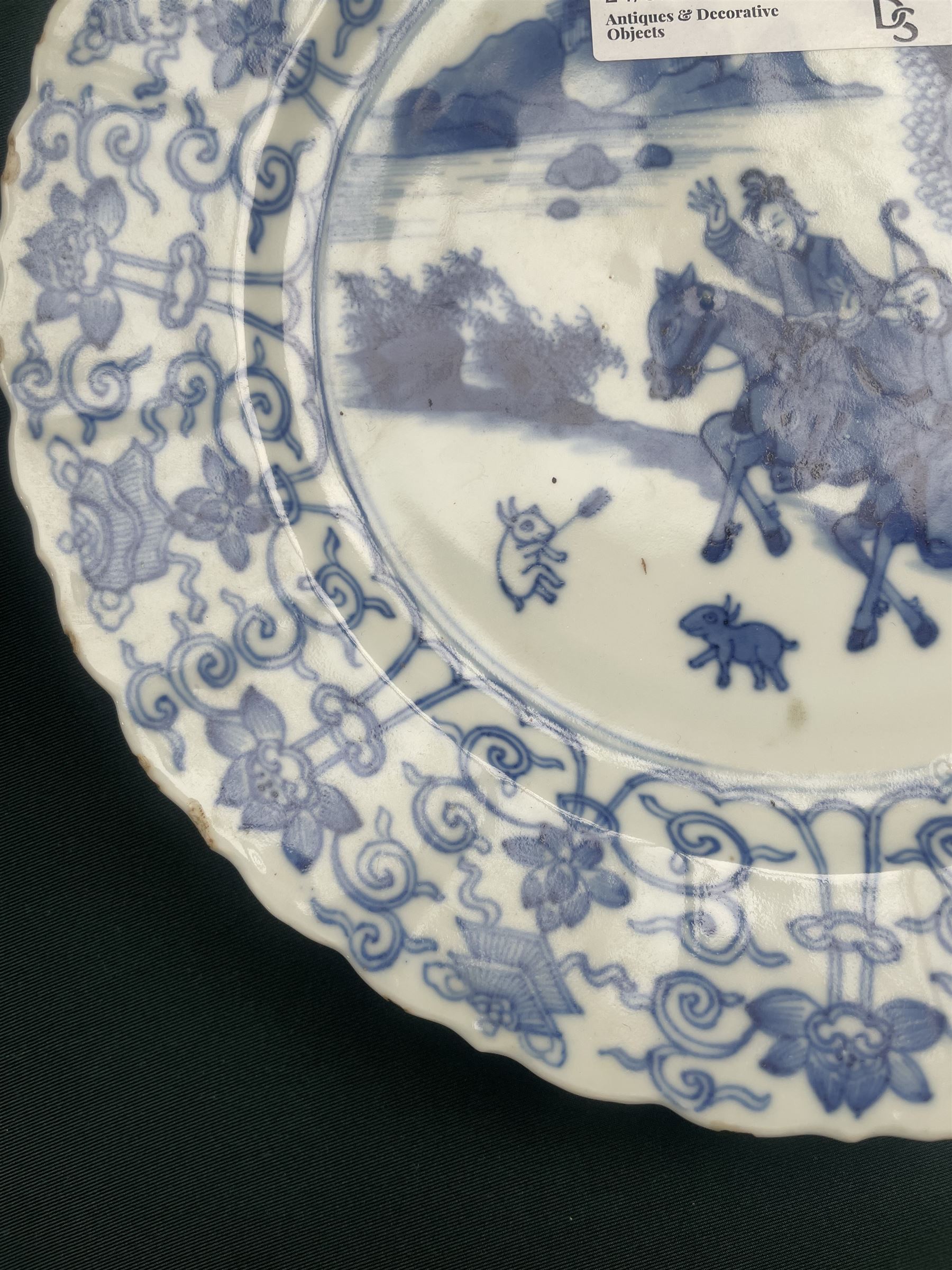 Chinese Kangxi style blue and white plate, decorated to the centre with a hunting scene  of two hunters on horse back, surrounded by a foliate boarder, with with six character double ring mark beneath