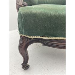 Set two Victorian rosewood drawing room armchairs, shaped and moulded frames carved with scrolls, the arms with scrolled terminals and shaped foliate carved supports, upholstered in green velvet, serpentine sprung seats, the cabriole supports carved with flower heads terminating at castors
