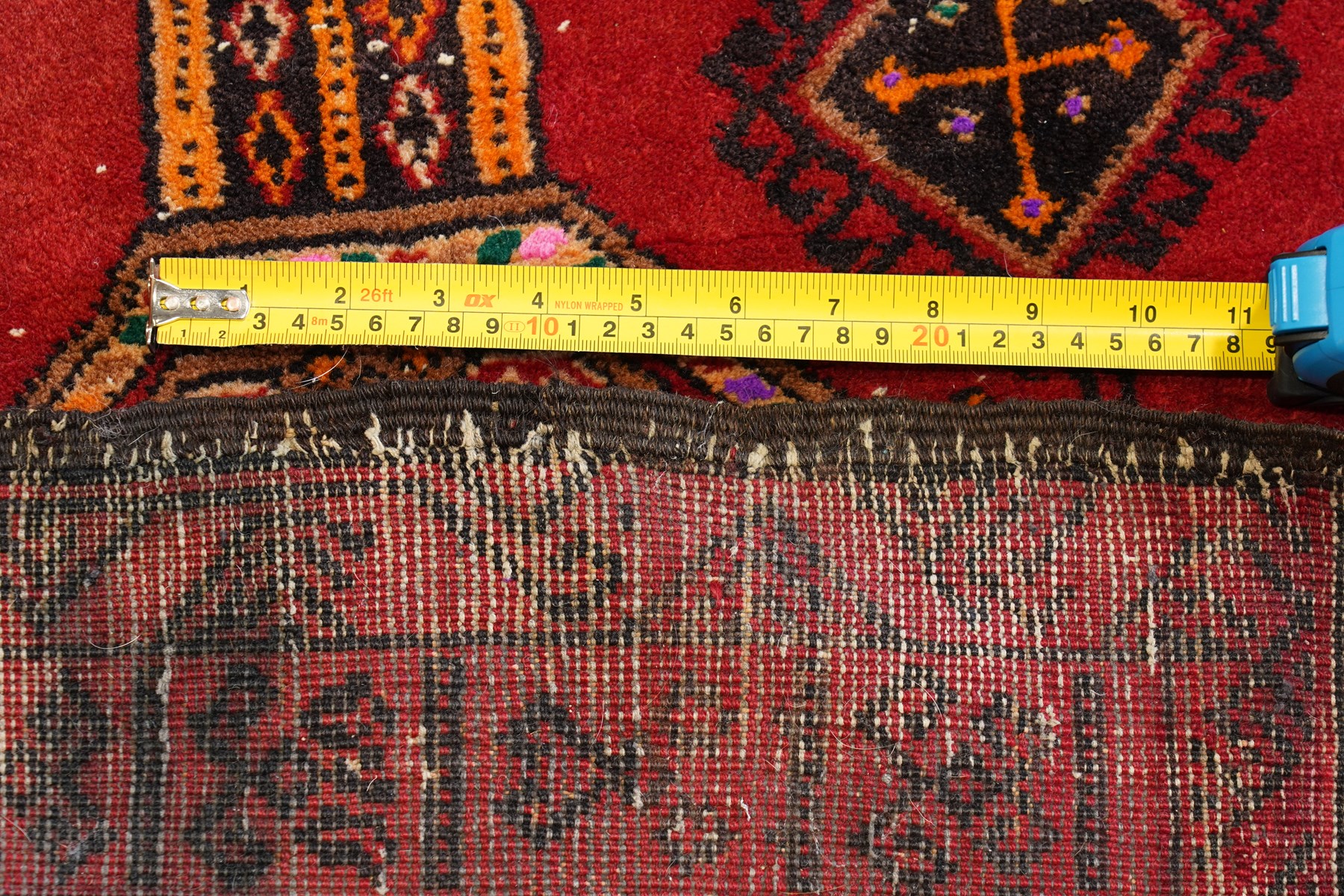 Persian Baluchi crimson ground rug, decorated with three columns of geomtric motifs