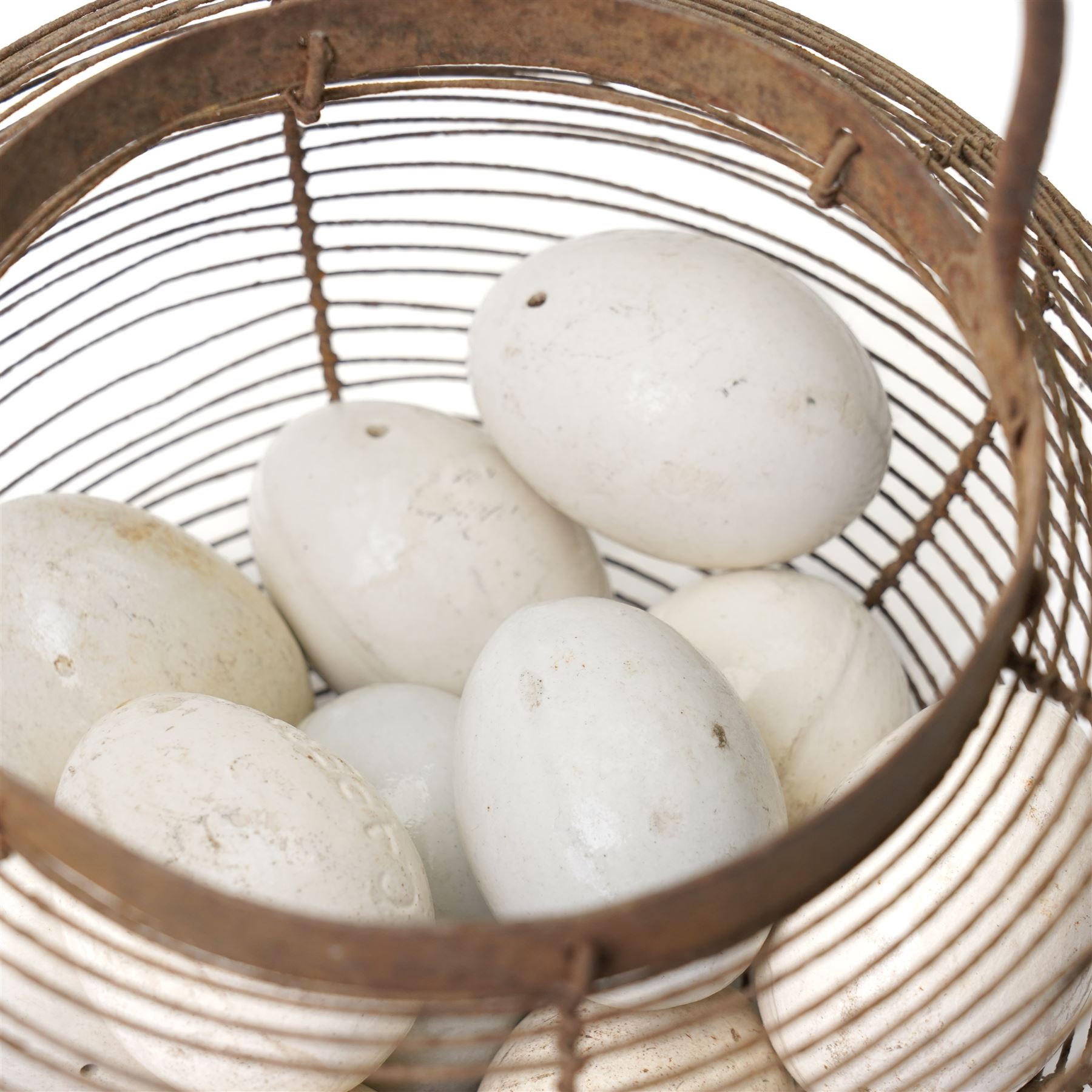 Wire crock containing 11 broody hen ceramic dummy eggs, two marked 'Caperns' 