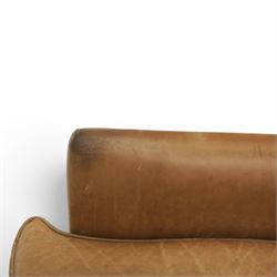 20th century tan leather armchair, the curved wing back above low square arms, shaped loose seat cushion with piped edge, close-nailed side detail, raised on concealed castors
