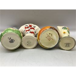 Group of Art Deco ceramics, comprising Wadeheath jug painted in spiralled bands of blue, orange, yellow and brown, shape no. 707784, Royal Doulton Caprice pattern twin handled bowl, no. D5358, Arthur Wood wall pocket of typical stylised fan form with painted floral decoration, Arthur Wood vase of cornucopia form with red and grey floral decoration, Wadeheath jug of ribbed form with stylised handle, and two Hancock's Ivory Ware jugs, tallest example H26cm