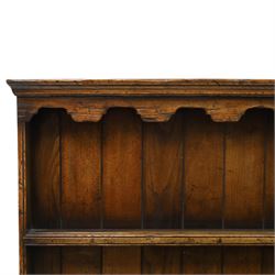 Georgian design oak dresser of small proportions, moulded cornice over open plate rack with two shelves and shaped apron, the base fitted with two drawers over three small drawers, brass drop handles, shaped apron, on square supports united by pot board