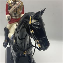 Mounted Lifeguard upon a black horse, in the style of Beswick, upon a wooden plinth, H31cm