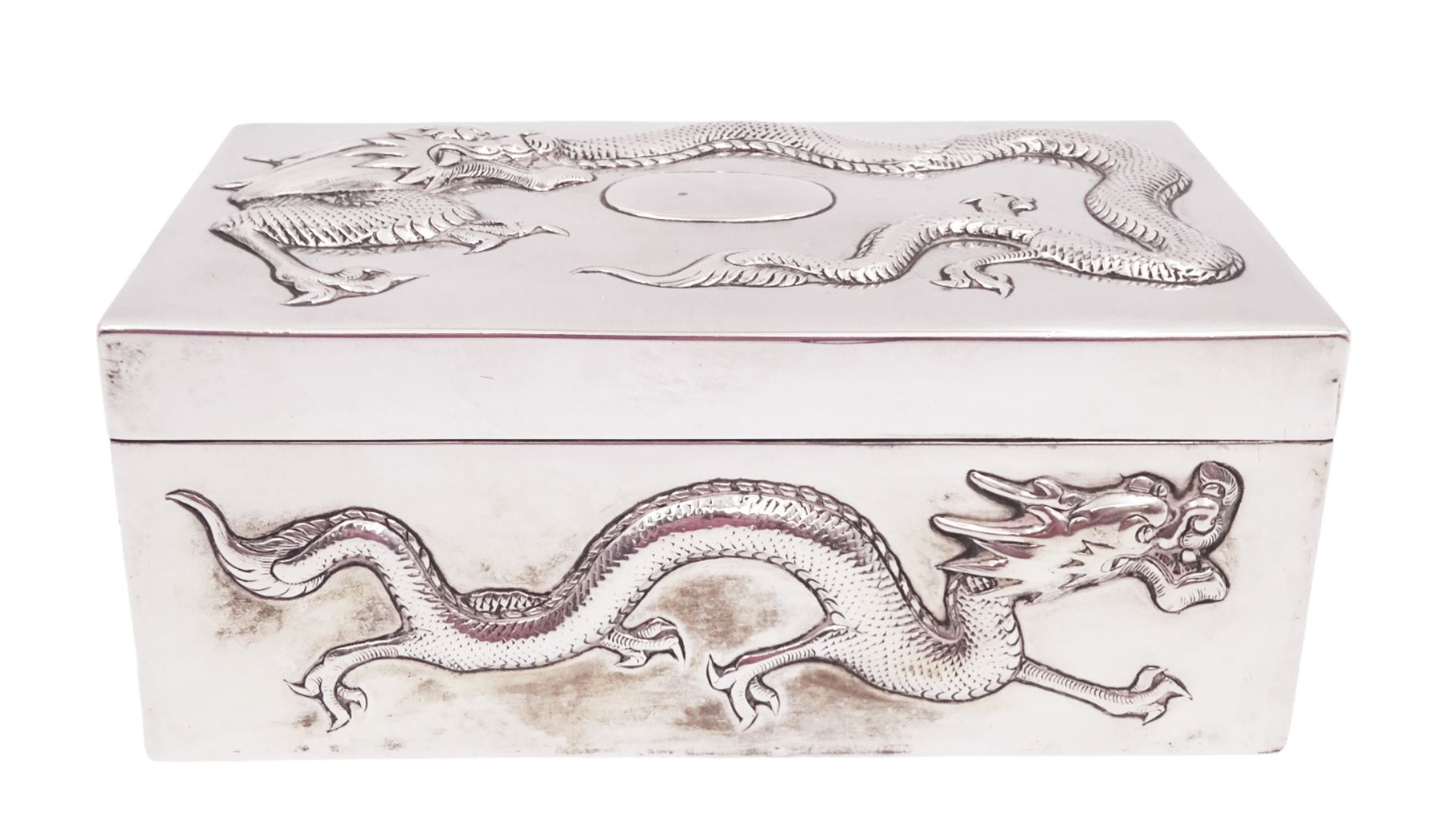 Late 19th century/early 20th century Chinese export silver mounted cigarette box, of rectangular form, decorated in relief with dragons, the hinged cover with similar dragon decoration and central blank oval cartouche, opening to reveal a softwood lined compartmentalised interior, stamped beneath with character mark and KMS for maker Kwong Man Shing, H6.3cm, W15.5cm, D9.5cm