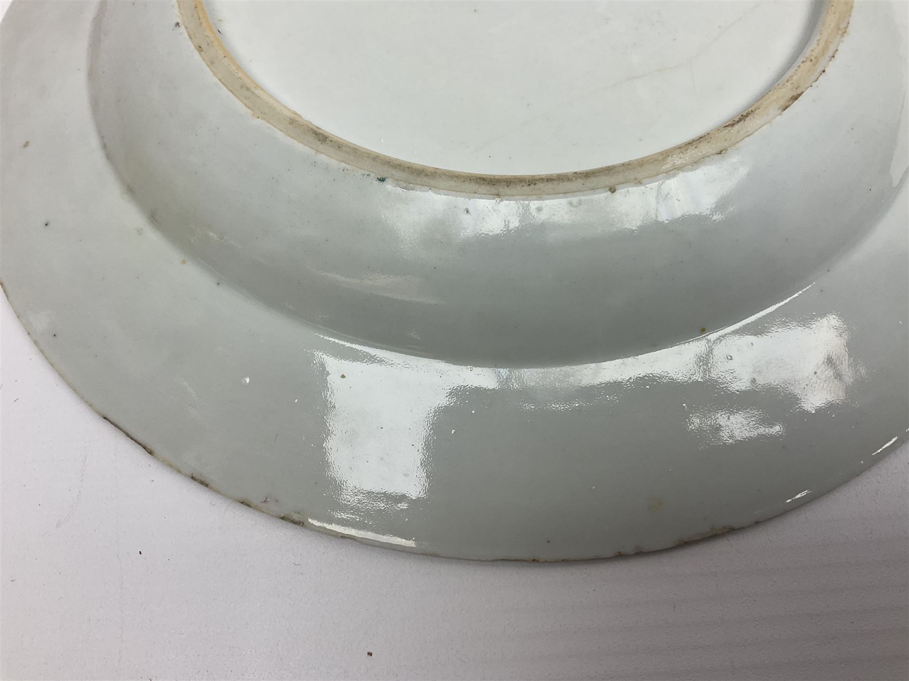 Three 18th century Chinese Famille Rose plates, the first example enamelled with blossoming peonies, rockwork and fence, the other two examples of similar design, decorated with blossoming peonies and sprigs within shaped inner borders, each approximately D23cm