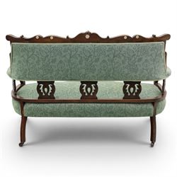 Edwardian mahogany framed sofa, shaped cresting rail with scroll terminals and carved foliate pediment, upholstered back and swept arms in green foliate fabric, pierced splat supports, serpentine front seat rail, on cabriole supports terminating in castors
