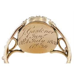George III 9ct rose gold garnet and pearl mourning ring, single cabochon garnet, with split and seed pearl surround and pierced design shoulders, the back inscribed and dated 1808