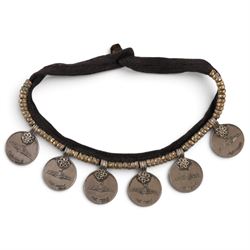 Collection of Middle Eastern jewellery, including silver necklace with a crescent  shaped pendent with beadwork and barrel tasselled ends, nickel silver wedding necklace with filigree decoration, coin bracelet, two bridal wedding caps and two others 
