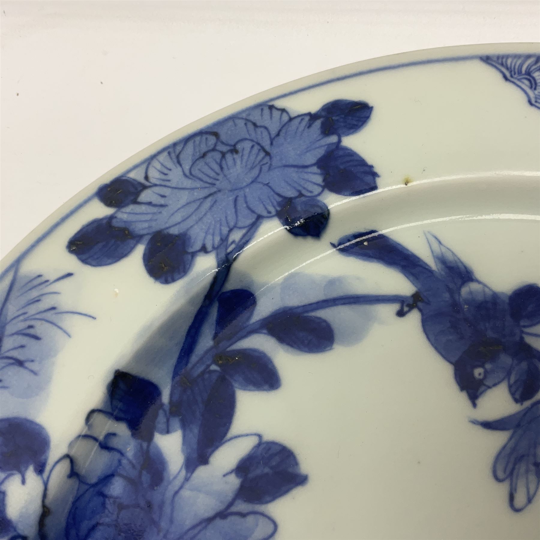 Japanese Meiji period Arita blue and white plate, of circular form, painted with riverside landscape and bird upon flowering branch, with character mark beneath, D24.5cm, together with two 18th century Chinese blue and white plates, each painted with floral design, each approximately D22.5cm