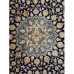 Central Persian Kashan hand-knotted carpet, the navy field with central medallion in pale blue and gold tones, surrounded by spiralling arabesques and palmettes, framed by quarter spandrels and a wide border of stylised lotus and rosette motifs between floral guard stripes, from the region of Kashan