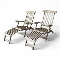 Pair of teak reclining garden steamer armchairs, each with an adjustable slatted back, curved slatted seat and footstool