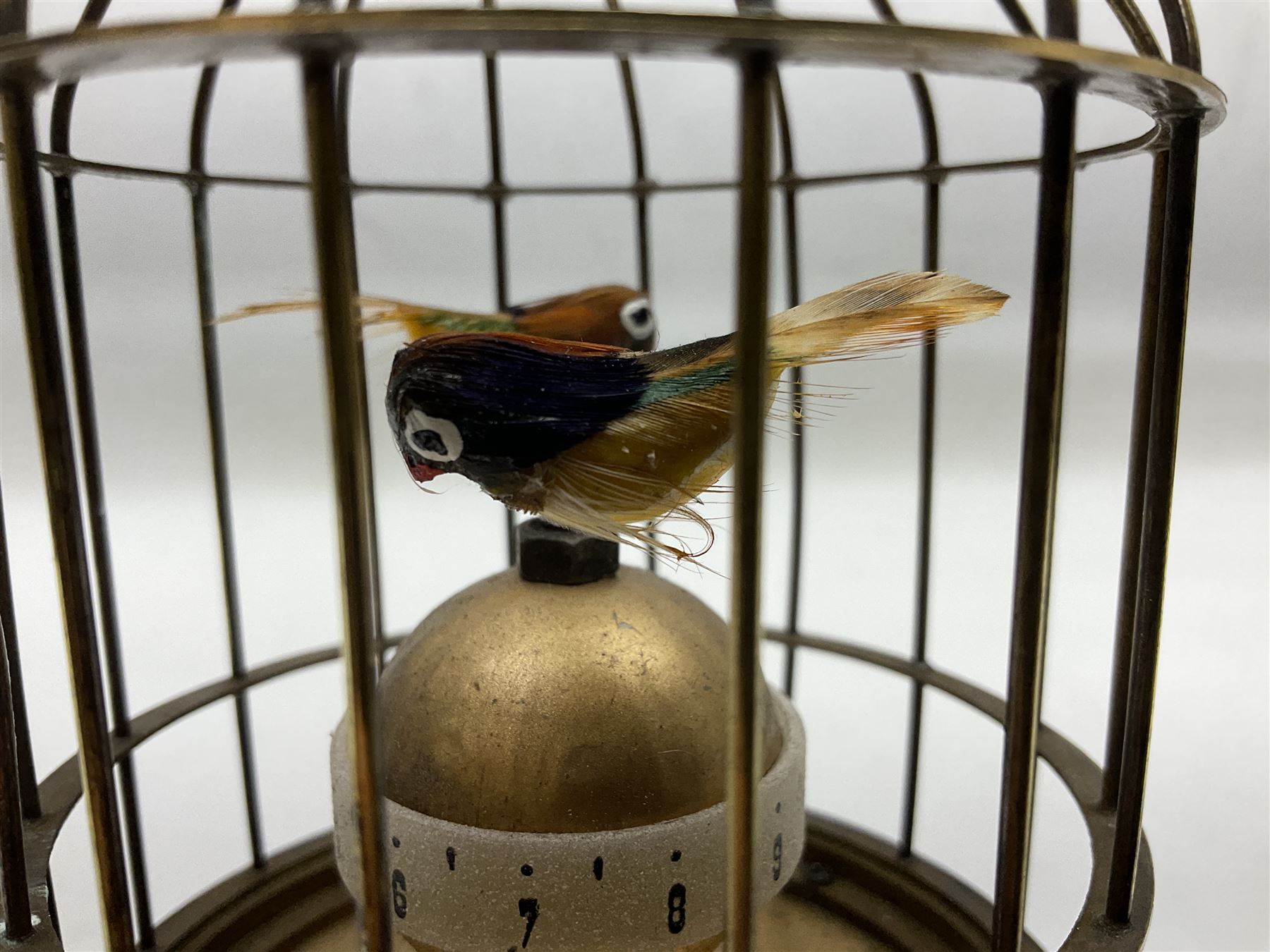 Automation bird cage clock of predominantly brass construction with central rotating orb and two birds with feathered decoration, H19cm