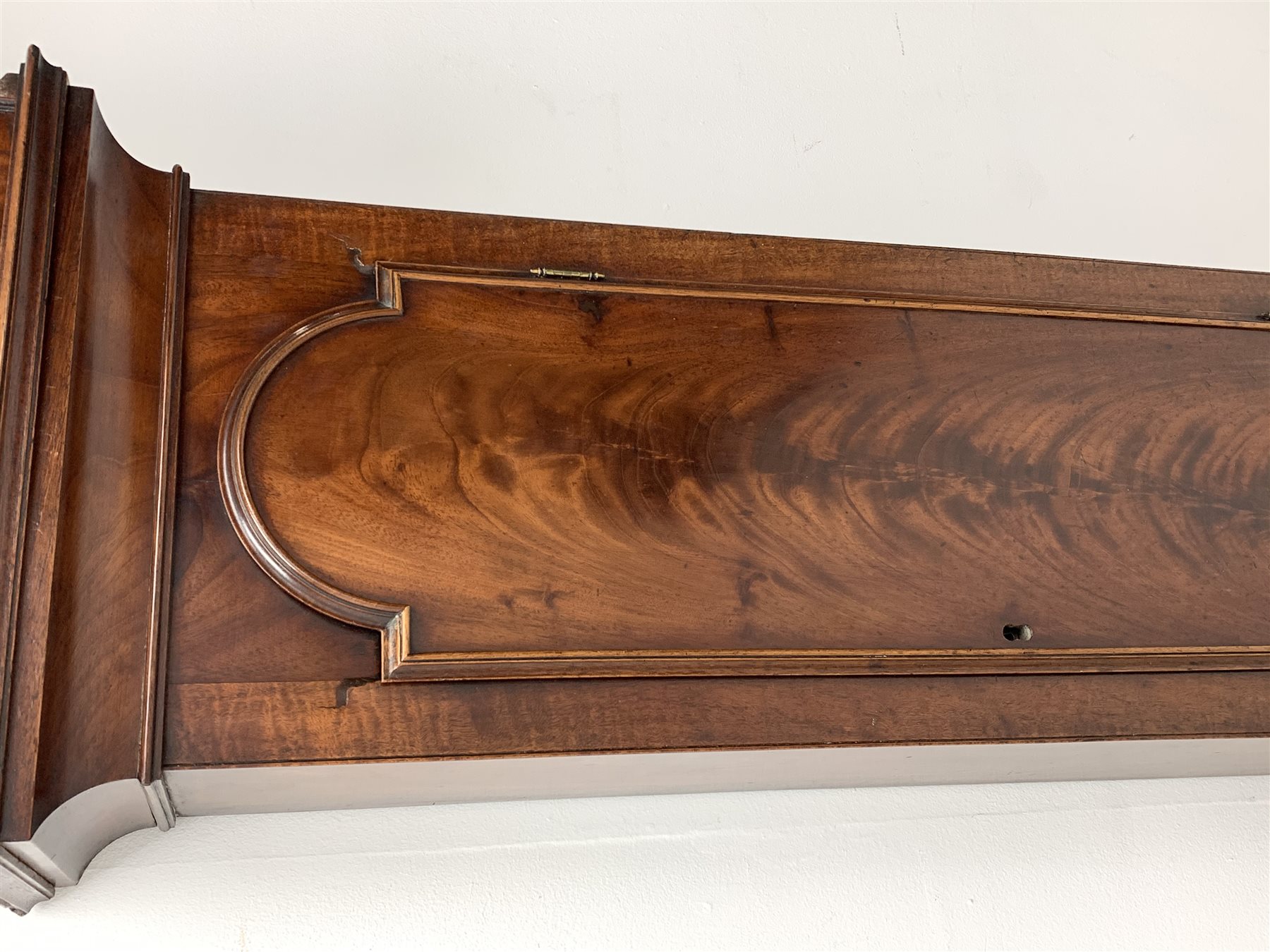 George III mahogany longcase clock, the hood with stepped moulded arch pediment above glazed door, fret work grille to each side, figured trunk door and base, enamel Arabic dial painted with country house scene and floral spandrels signed 'S. Wright, Watford', subsidiary seconds dial and date aperture, eight day movement striking the hours on bell, H212cm (two weights and pendulum)