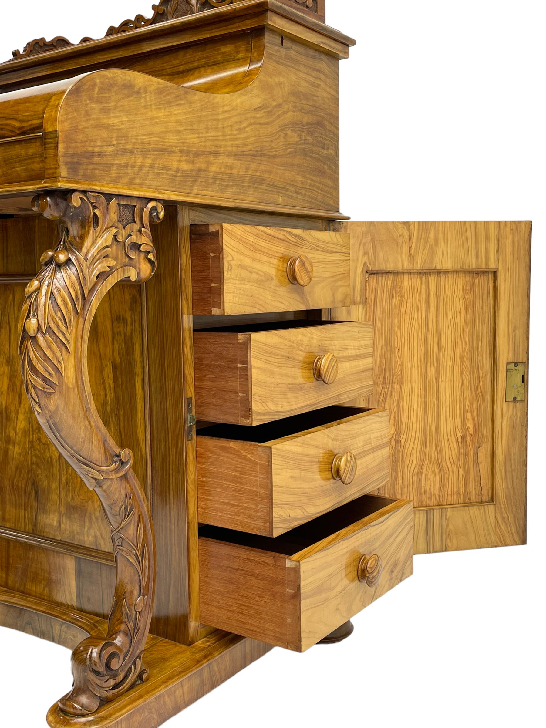 Fine and unusual 19th century olivewood piano top davenport, raised shaped back carved with olive branches and olives, the top hinges to reveal lidded and correspondence compartments, the piano lid enclosing sliding top with hinged and adjustable writing surface with leather inset, right-hand panelled door enclosing four drawers, olive branch and scroll carved cabriole front supports on moulded and shaped platform, turned cup feet with recessed castors 