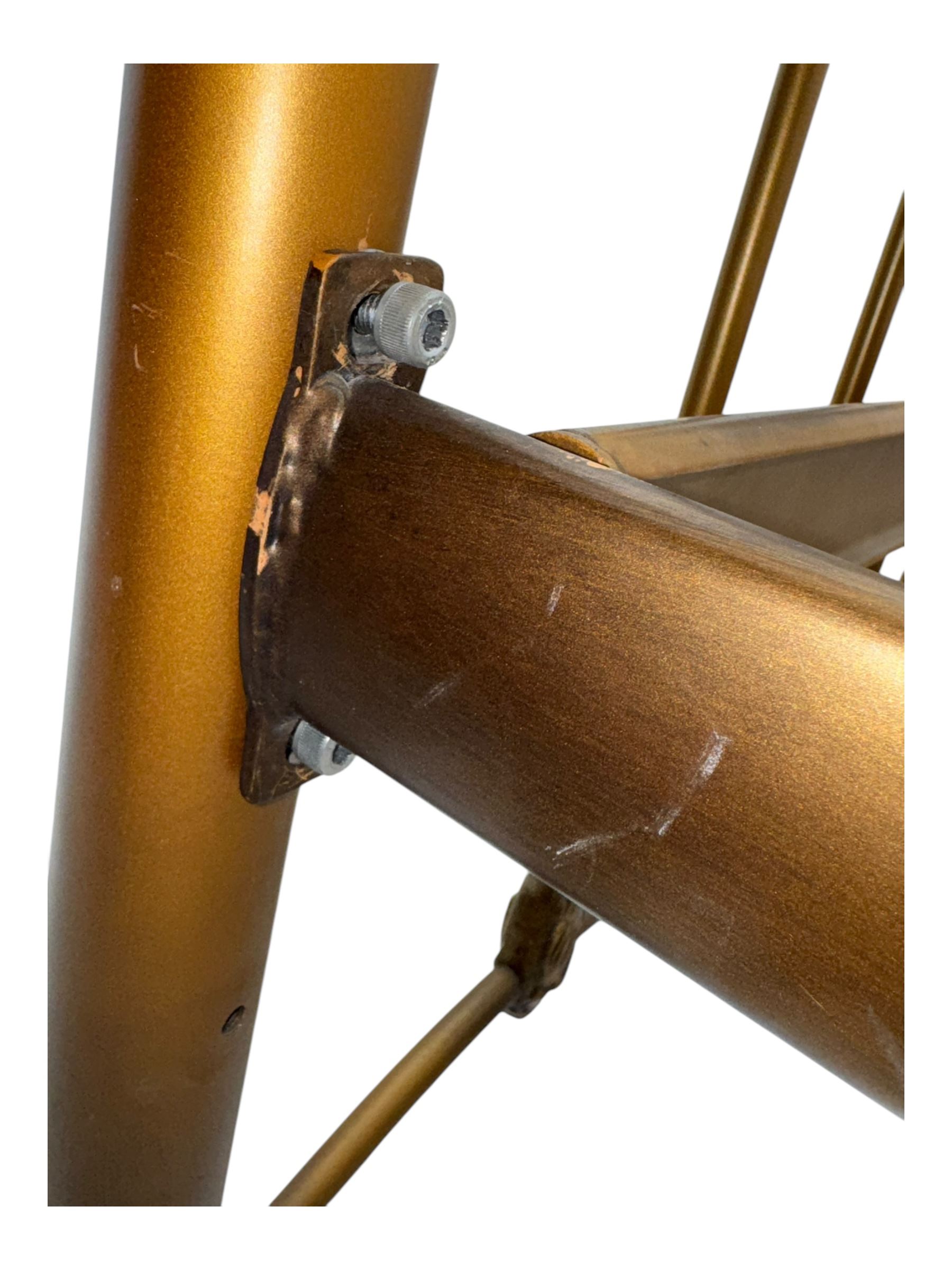 Victorian design king size brass bed frame, featuring an arched headboard and footboard with intricate cast floral and scrollwork centre motifs, flanked by cylindrical supports with ball finials and decorative collars, raised on rounded feet, with a slatted wooden base