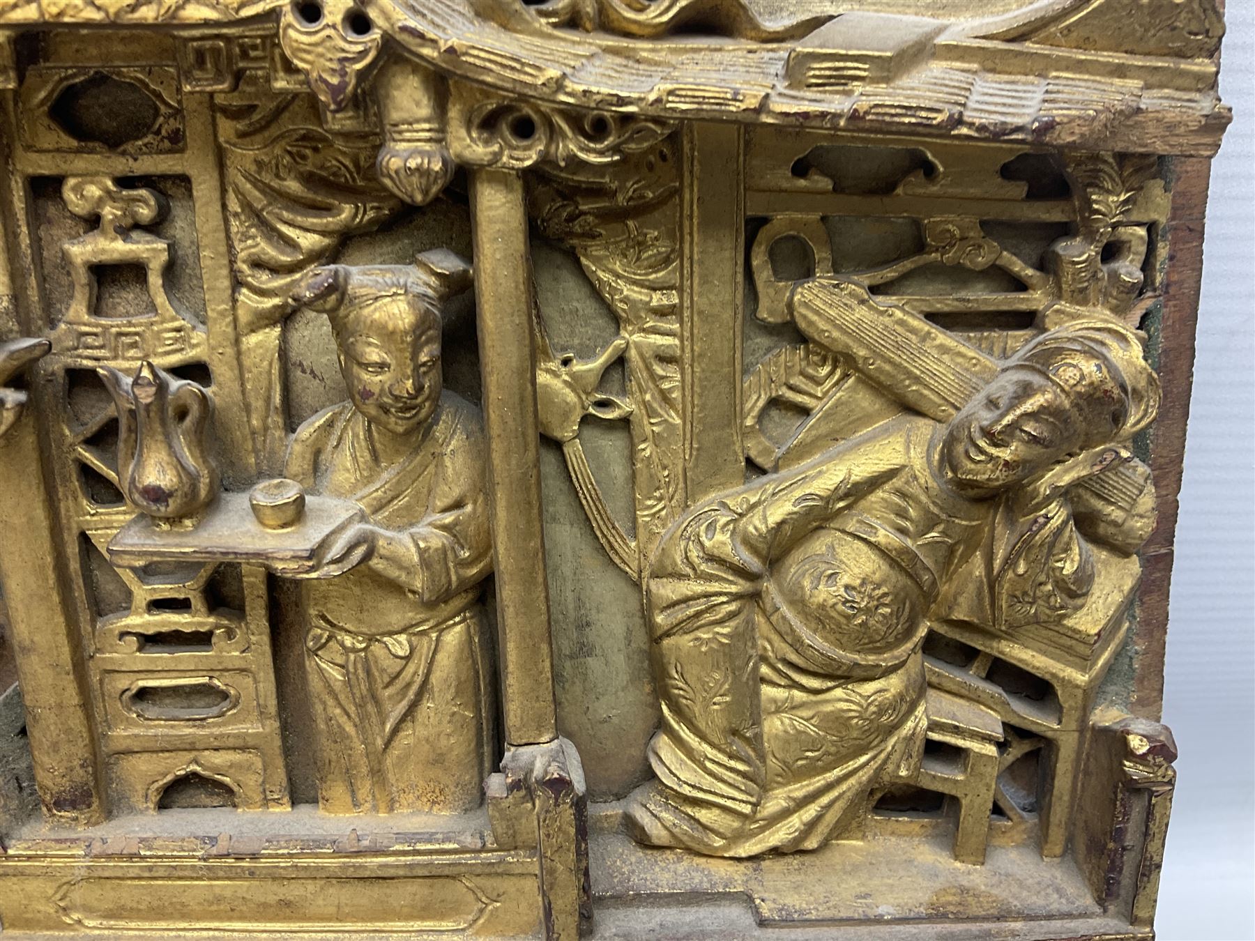 Two carved oriental wall hangings, the first example gilded depicting a temple and garden scene, the second figures in a garden, L49cm