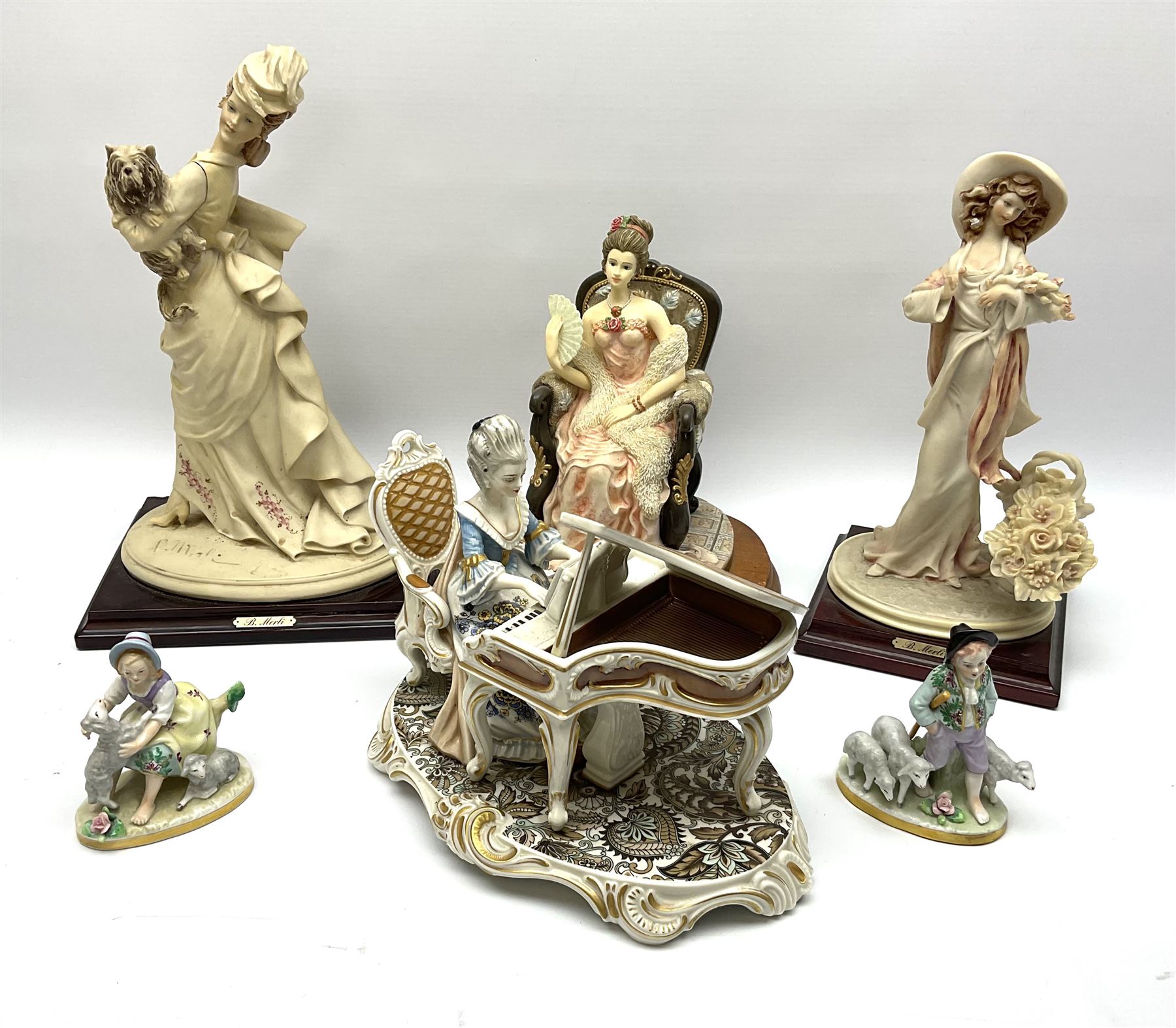 A small pair of Sitzendorf figures modelled as shepherd and shepherdess, H10.5cm together with a Dresden porcelain figure modelled as a female figure playing the piano, H17cm, a Naples figure with floral bouquet, H27.5cm,  a Naples figure holding a dog, H33cm, and a Leonardo Collection figure, Interlude, H24cm. 