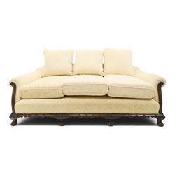 Quality Edwardian carved mahogany lounge suite comprising three-seater settee and pair of armchairs, the sofa with arched back over rolled arms and deep sprung seat, the arm terminals carved with acanthus rosette over gadroon and rope-twist moulding, the shaped apron carved and moulded with scrolling foliate acanthus motifs, terminating to four large front hairy paw and ball feet, upholstered in pale yellow foliate fabric with matching seat and scatter cushions (W200cm D105cm H73cm); the matching deep armchairs (W78cm D95cm H75cm)