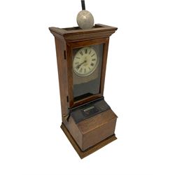 An early 20th century time recording clock (clocking in machine) manufactured by the International Time Recording Company, in an oak case with a glazed door and sloping desk, with a circular dial within a silvered slip, Roman numerals, minute track and steel spade hands, crank handle and bell. With pendulum and keys. 


