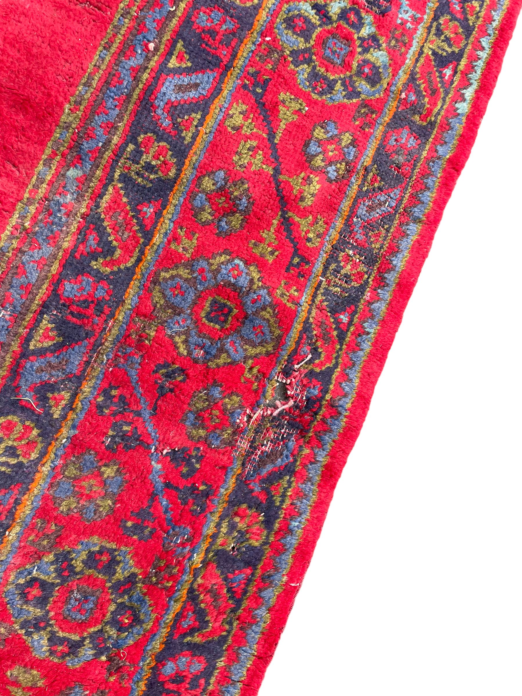 Early 20th century Western Anatolia Turkish Oushak crimson ground carpet, the field decorated with rows of Herati and Palmette medallions, the main border decorated with stylised flower head motifs within guard stripes
