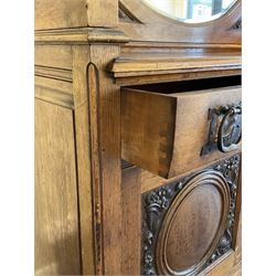 Late 19th century Arts & Crafts period oak mirror back sideboard, shaped bevelled mirror back carved with foliate scrolls and flower heads, down swept supports with elongated club-shaped uprights, moulded rectangular top over two drawers and three cupboards, the drawer fronts with copper handles decorated with sailing ships, panelled doors carved with mythical beasts, flowerheads and foliage, on moulded block feet