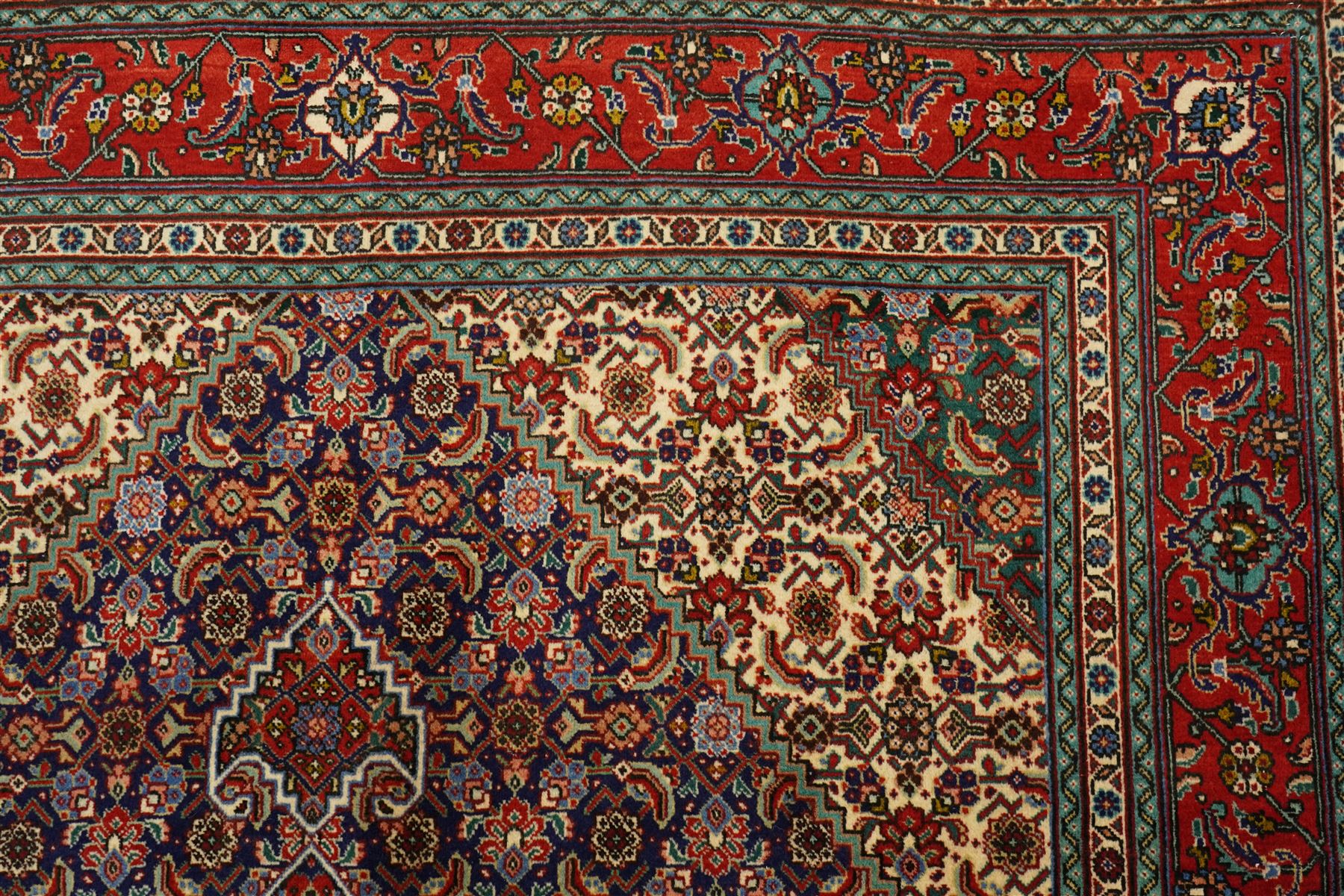 North West Persian Tabriz hand-knotted rug, ivory field with a central lozenge medallion in deep indigo and madder red, enclosing a inner reserve with stylized floral motifs, spandrels with angular floral sprays, main border of repeating floral vinery and palmettes, framed by multiple guard borders, with cotton fringe ends