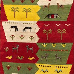 South West Persian Qashqai kilim, the field arranged with stepped polychrome panels depicting stylised camels, goats, cattle and birds, interspersed with trees and flowering stems, enclosed by a red border with multicoloured geometric devices