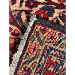 Persian Hamadan indigo and red ground carpet, large central medallion decorated with projecting palmette motifs, the surrounding field decorated with trailing branches and flower heads, crimson ground border decorated with stylised plant motifs, within floral pattern guard stripes 