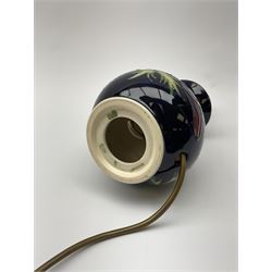 A Moorcroft table lamp, of baluster form, decorated in the Anemone pattern upon a dark blue ground, with impressed marks beneath, with accompanying cream shade with piped detail, overall H38.5cm.