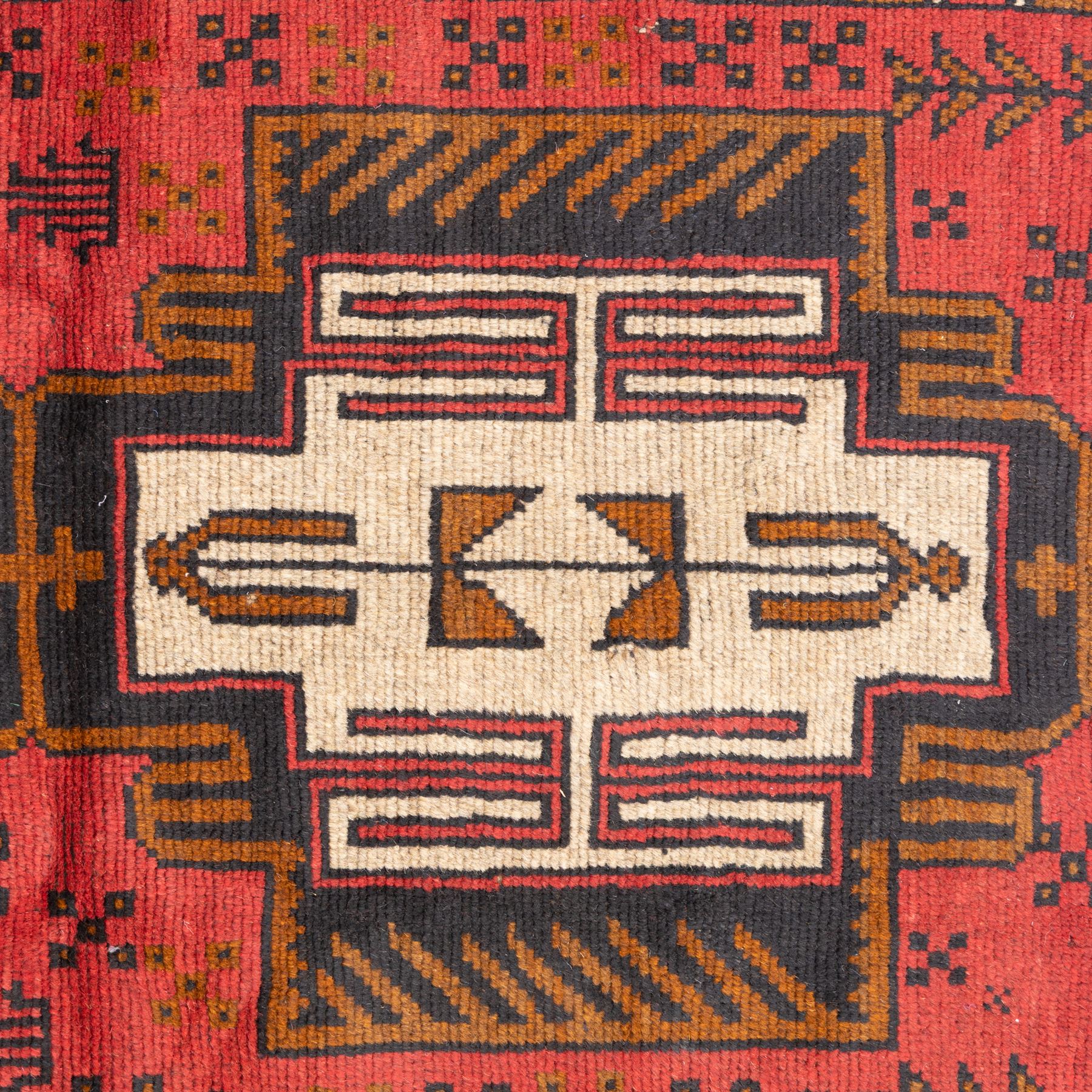 Turkish Anatolian rug, crimson ground, with stepped geometric medallions in ivory, brown, and black within angular striped borders in tones of red and ochre 