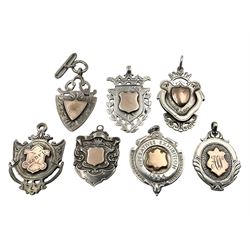 Seven early 20th century silver gold faced cartouche fobs, to include a double sided example, bordered by laurel leaves and six others, all hallmarked with various dates and makers
