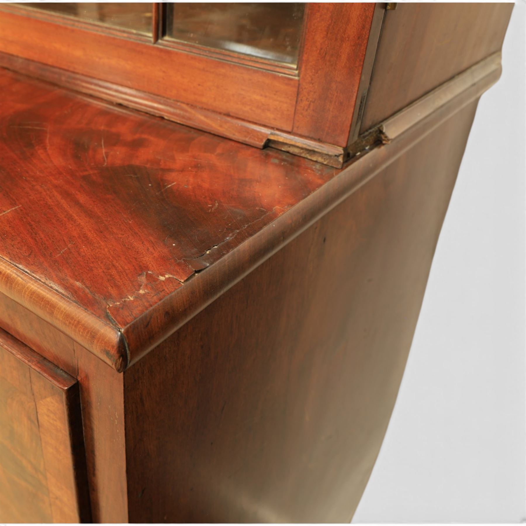 Early 19th century mahogany secretaire-bookcase, projecting cornice above astragal glazed cabinet with adjustable shelved interior, fall front secretaire drawer, fitted interior with pigeonholes and drawers, flame mahogany fronted cabinet with three drawers, on turned supports 