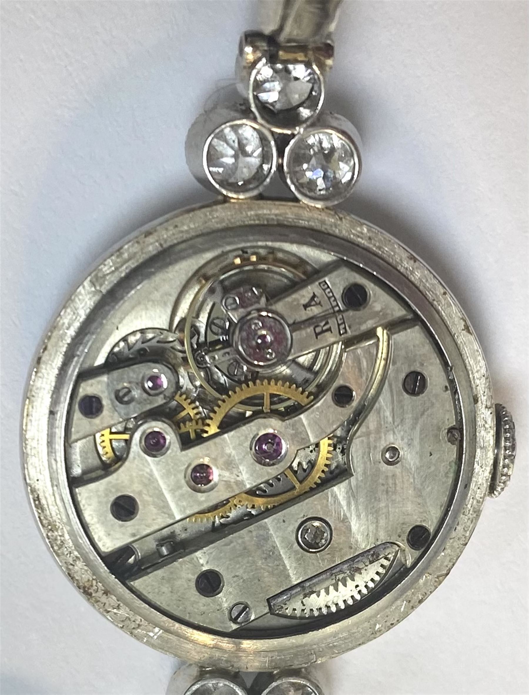 Platinum Art Deco milgrain set diamond manual wind lever wristwatch, cream enamel dial with Arabic numerals, diamond set bezel, the case spaced by two groups of three diamonds of approx 0.20 carat each, to a platinum expanding link bracelet, the first two links on each side set with diamonds, back case stamped 8942 and initialled JF with Fleur de Lys mark sitting between the letters