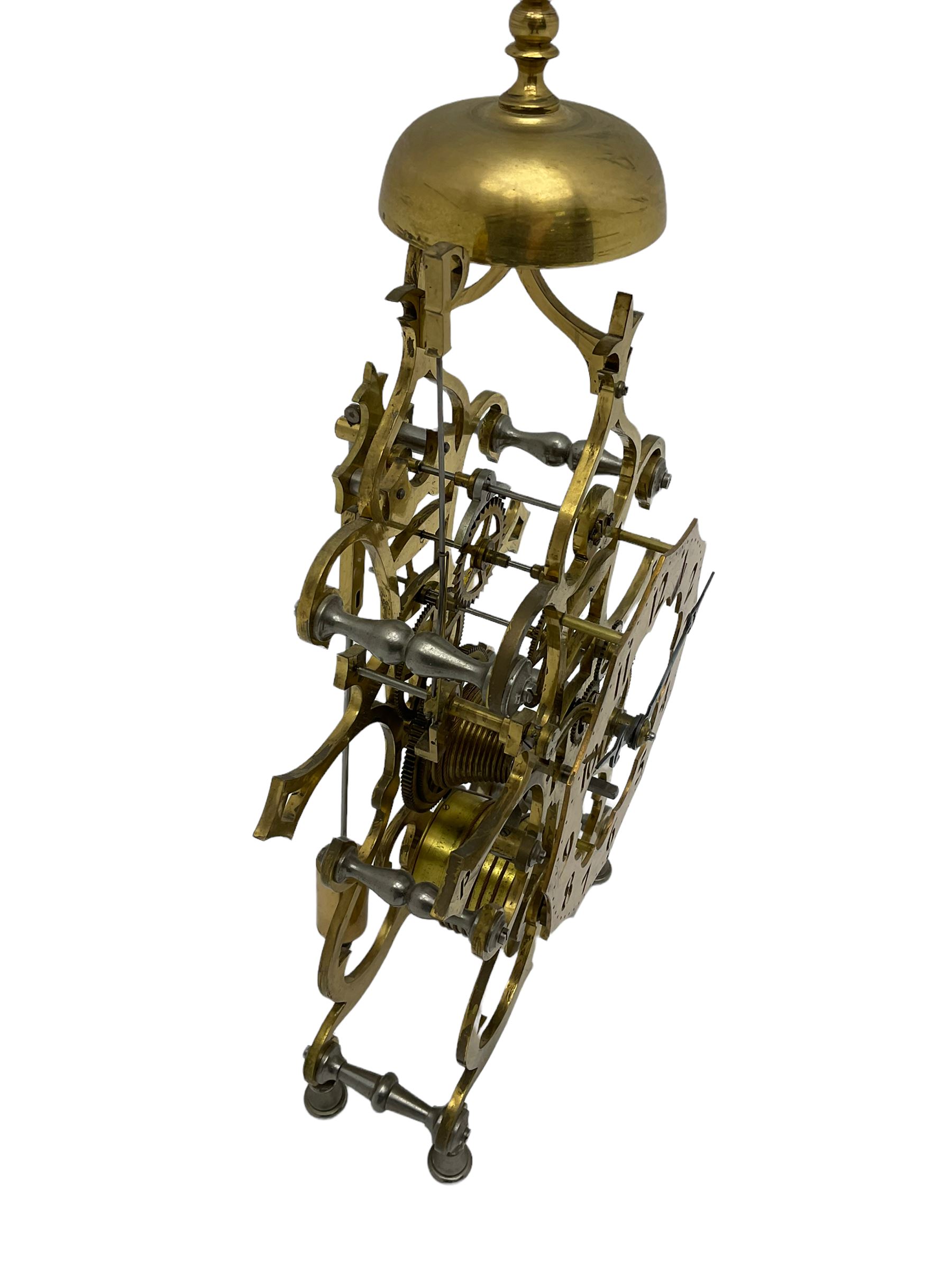 20th century scroll pattern Skeleton clock to the construction design of John Wilding, with an 8-day fusee movement and passing strike, with lantern pinions and brass wheels, Skeletonised brass dial with pierced Arabic numerals, cylindrical pendulum bob, with bespoke key and original construction book. 
John Wilding was a highly respected engineer and clockmaker publishing many books on the construction and repair of Fusee and weight driven clocks.

