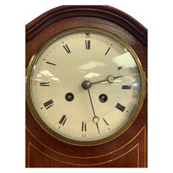 Edwardian-French 8-day mantle clock in a mahogany case with satinwood inlay, on a narrow plinth raised on ball feet, enamel dial with Roman numerals and steel moon hands, rack striking movement, sounding the hours and half hours on a gong. With pendulum and key.
