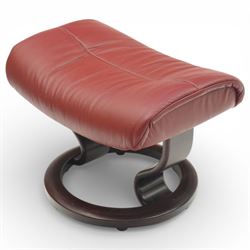 Ekornes - Stressless reclining armchair and matching footstool, upholstered in oxblood leather with padded headrest and segmented back cushion, shaped armrests with exposed adjustment handles, raised on stained laminated beech circular swivel base, the conforming stool on matching ring base