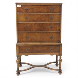 Georgian style walnut chest on stand, the figured top section fitted with four long drawers above a further drawer on the base, brass swan-neck handles, on turned legs joined by shaped stretchers with bun feet