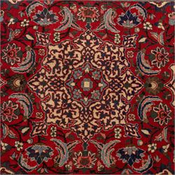 Central Persian Isfahan hand-knotted rug, madder red field, with elaborate central medallion with pendants and scrolling arabesques, palmettes and stylized floral sprays arranged in a densely ornamented ground of classical Safavid inspiration, ivory border with a continuous vine scroll of palmettes and rosettes, flanked by multiple guard stripes in navy and red with geometric and floral motifs, with cotton fringe ends 