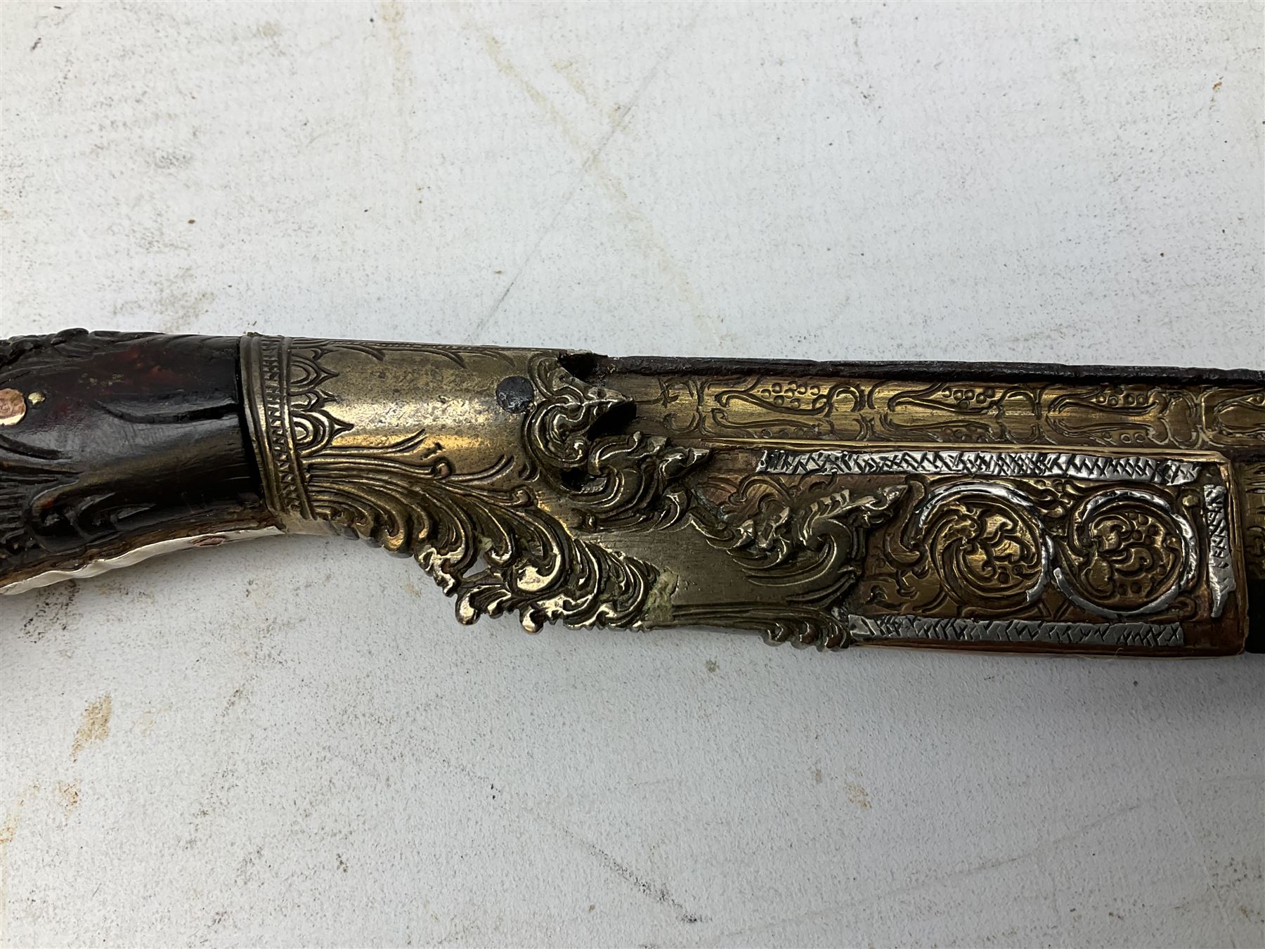 19th century Singhalese knife pia kaetta, the 20cm steel blade inset with yellow and white metal, with metal mounted carved pistol grip, in plain wooden scabbard L33cm overall